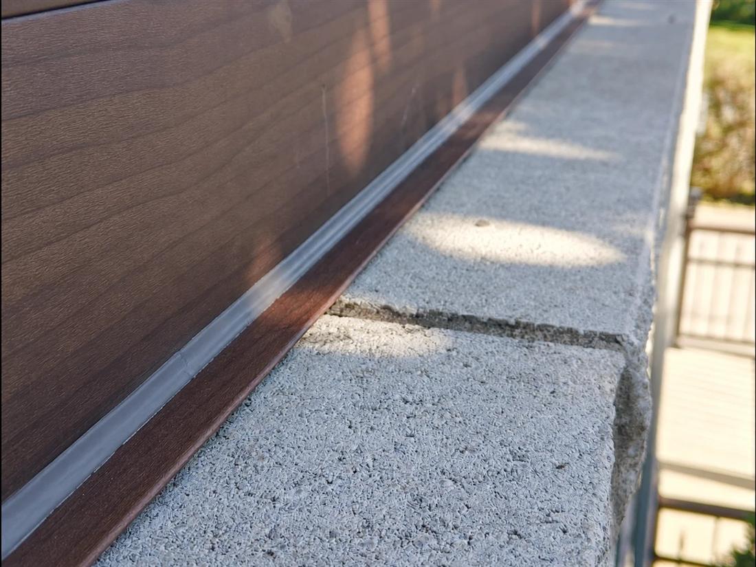 Gros plan d'un joint de calfeutrage parfait le long du revêtement et du rebord de béton