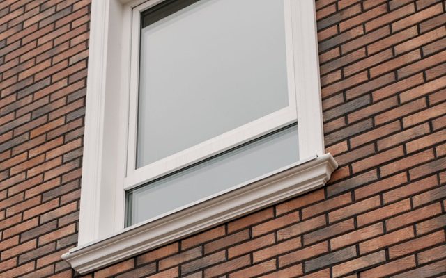 Fenêtre neuve dans la brique, joints blancs nets tout autour du cadre