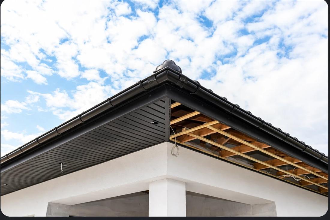 Coin de toit avec soffite et gouttière noirs posés sur une maison blanche